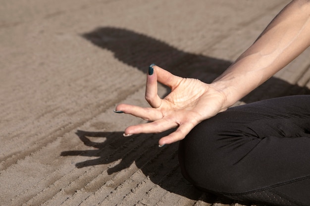 Kostenloses Foto frau, die eine yoga-pose am strand hält