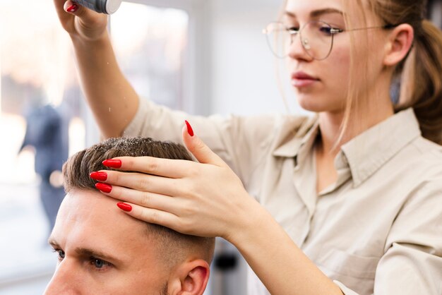 Frau, die einem Kunden einen Haarschnitt am Salon gibt