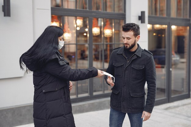 Frau, die einem Mann Schutzmaske gibt