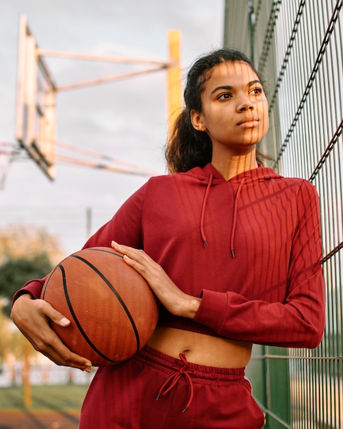 Frau, die einen Basketball draußen hält