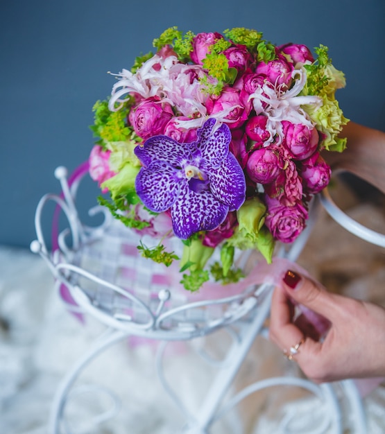 Frau, die einen Blumenstrauß innerhalb des weißen Hochzeitszubehörs einsetzt