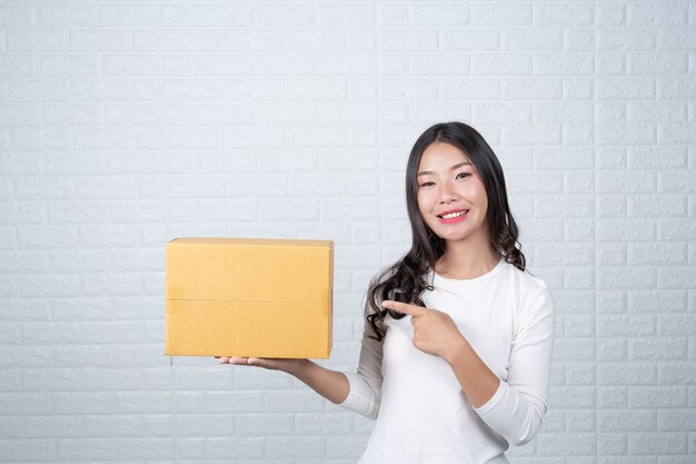 Frau, die einen braunen Briefkasten hält Machte Gesten mit Gebärdensprache.