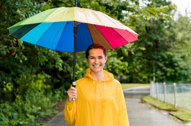 Frau, die einen bunten Regenschirm über ihrem Kopf hält