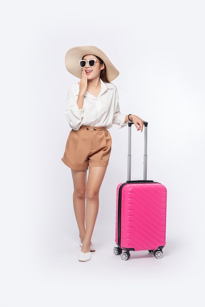 Frau, die einen Hut, eine Brille und die Griffe der Koffer trägt, um zu reisen