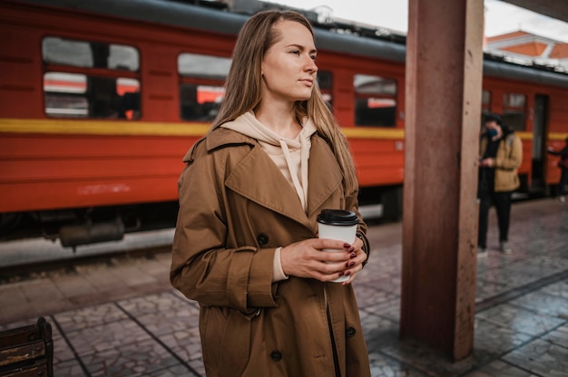 Frau, die einen Kaffee im Bahnhof hält