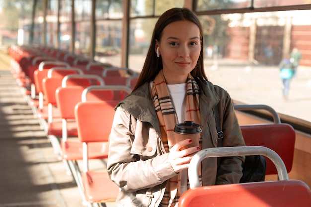 Frau, die einen Kaffee im öffentlichen Straßenbahnverkehr hält