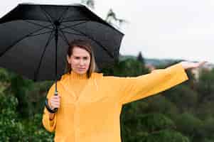 Kostenloses Foto frau, die einen offenen schwarzen regenschirm hält