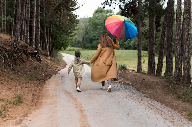 Frau, die einen Regenschirm und ihren Sohn an der Hand hält