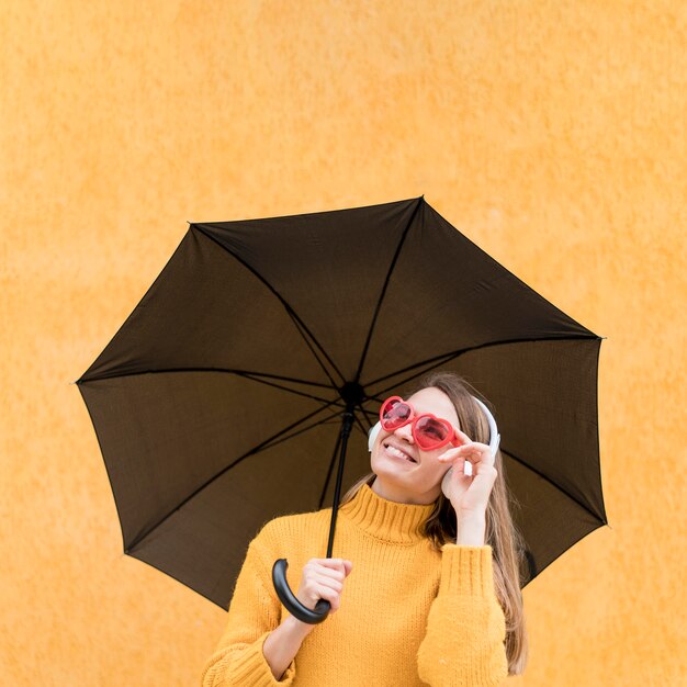 Frau, die einen schwarzen Regenschirm hält