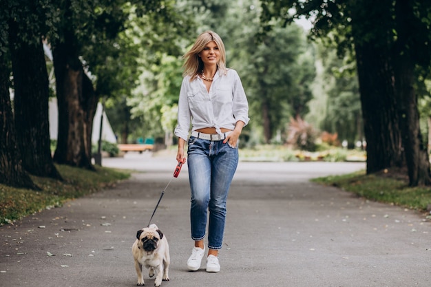 Frau, die einen Spaziergang im Park mit ihrem Mops-Haustier hat