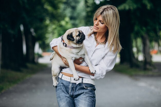 Frau, die einen Spaziergang im Park mit ihrem Mops-Haustier hat