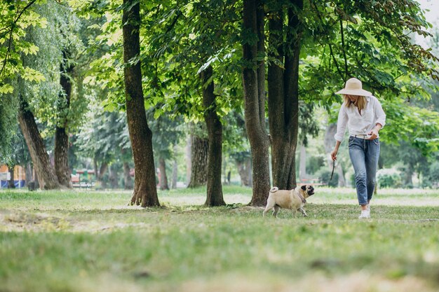 Frau, die einen Spaziergang im Park mit ihrem Mops-Haustier hat