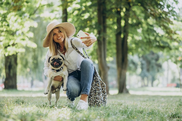 Frau, die einen Spaziergang im Park mit ihrem Mops-Haustier hat