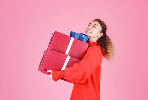 Frau, die einen Vorrat an großen Geschenkboxen trägt.