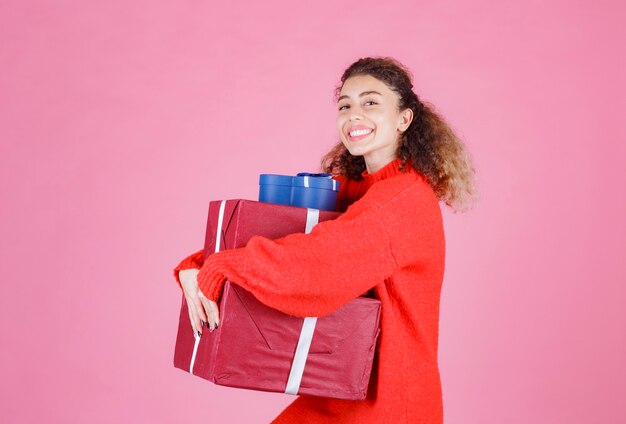 Frau, die einen Vorrat an großen Geschenkboxen trägt.