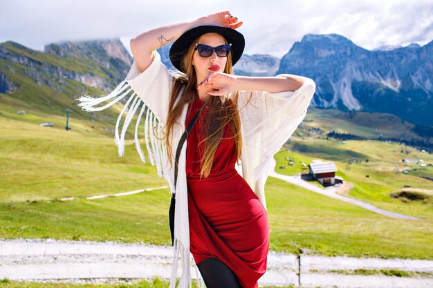 Frau, die elegantes Luxus-Boho-Stil-Outfit trägt und in erstaunlichen Dolomitenbergen posiert