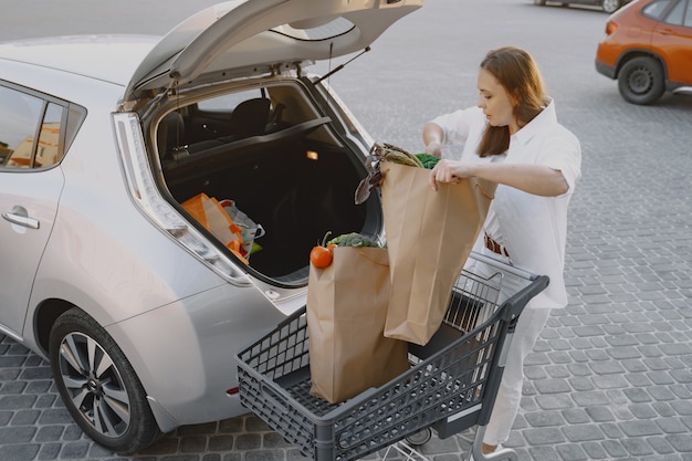 Frau, die Elektroauto an der elektrischen Tankstelle auflädt