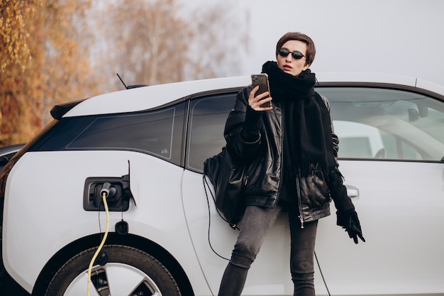 Kostenloses Foto frau, die elektroauto an der straße auflädt