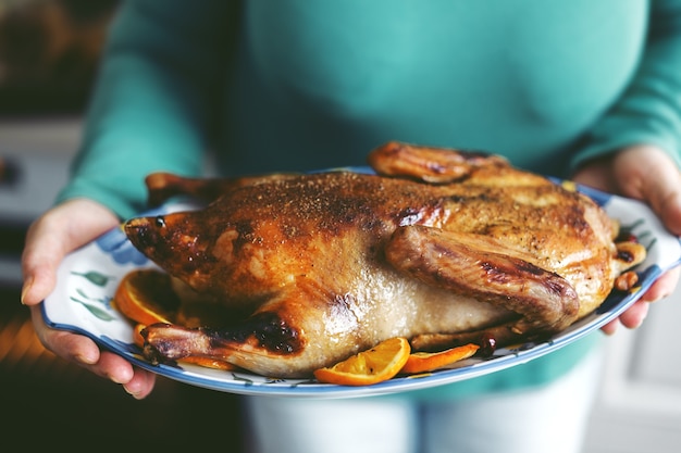 Frau, die Ente mit Gemüse kocht und es vom Ofen setzt. Lebensstil. Weihnachts- oder Erntedankkonzept.