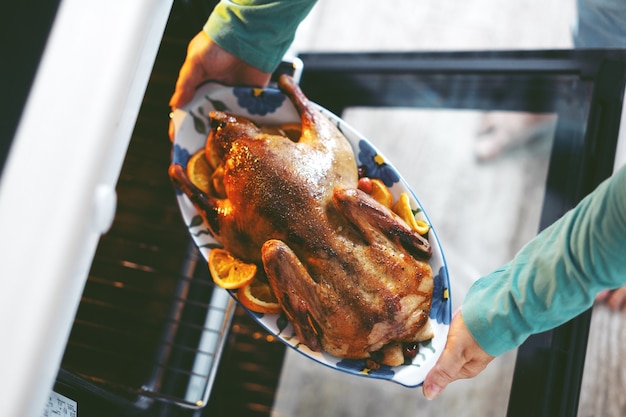 Frau, die Ente mit Gemüse kocht und es vom Ofen setzt.