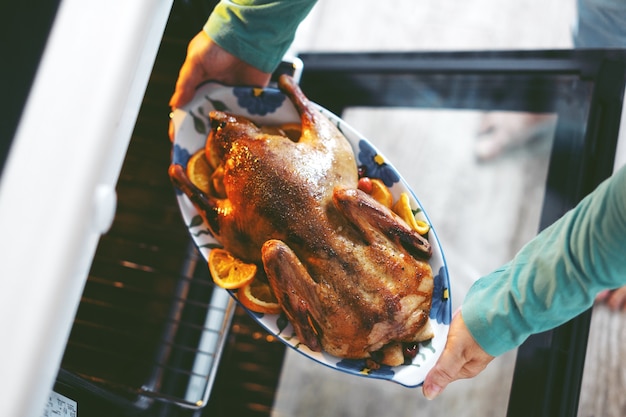 Kostenloses Foto frau, die ente mit gemüse kocht und es vom ofen setzt.