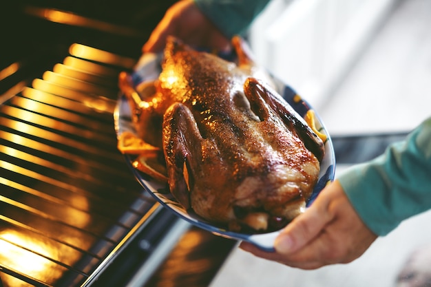 Frau, die Ente mit Gemüse kocht und es vom Ofen setzt.