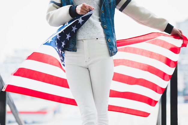 Frau, die entfaltete amerikanische Flagge hinter Beinen hält