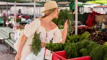 Kostenloses Foto frau, die etwas dill vom marktplatz riecht