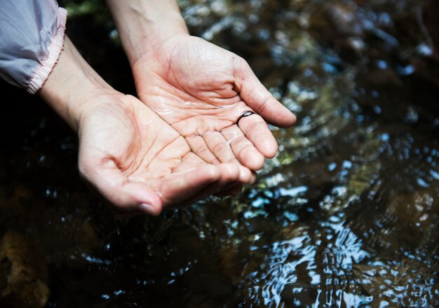 Frau, die etwas Wasser vom Fluss erhält, um zu trinken