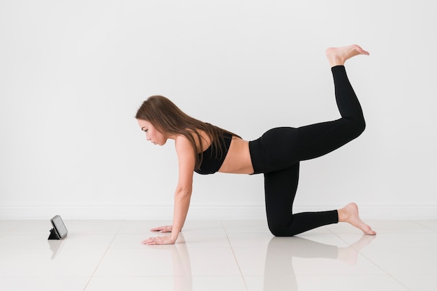 Frau, die Fitnessübungen vom Handy macht