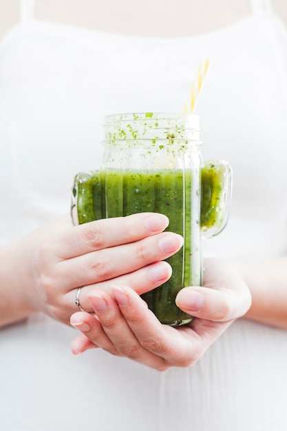 Frau, die Flasche grünen Smoothie hält