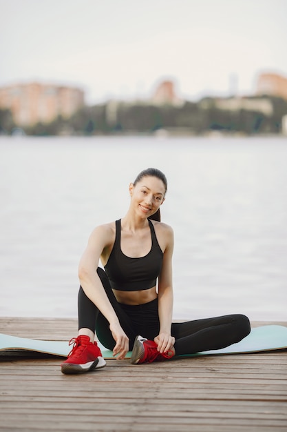 Frau, die fortgeschrittenes Yoga am Wasser praktiziert