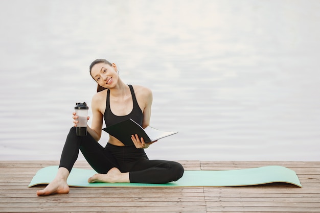 Frau, die fortgeschrittenes Yoga am Wasser praktiziert