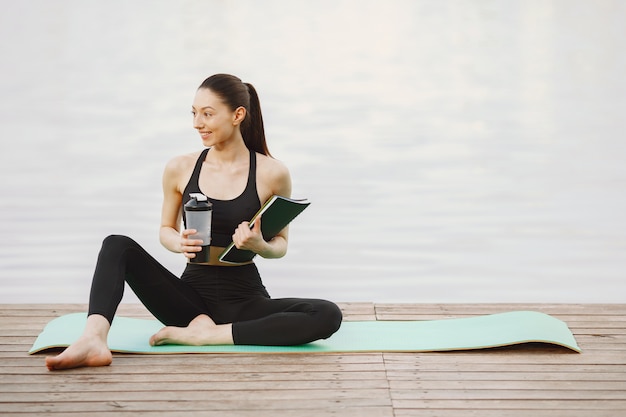 Frau, die fortgeschrittenes Yoga am Wasser praktiziert