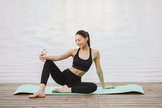 Frau, die fortgeschrittenes Yoga am Wasser praktiziert