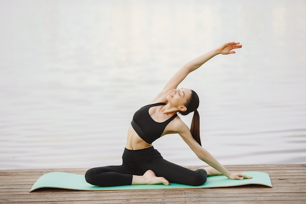 Frau, die fortgeschrittenes Yoga am Wasser praktiziert