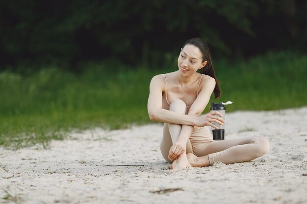 Frau, die fortgeschrittenes Yoga an einem Sommerstrand praktiziert