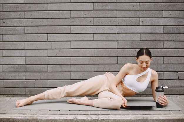 Frau, die fortgeschrittenes Yoga gegen eine dunkle Stadtmauer praktiziert