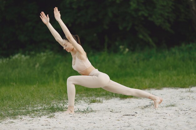 Frau, die fortgeschrittenes Yoga in einem Strand praktiziert