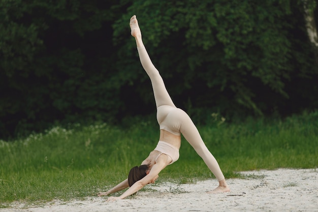 Frau, die fortgeschrittenes Yoga in einem Strand praktiziert