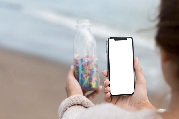 Frau, die Foto der Flasche mit Plastik nimmt