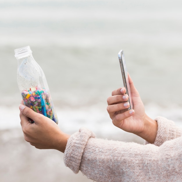 Frau, die Foto der Flasche mit Plastik nimmt