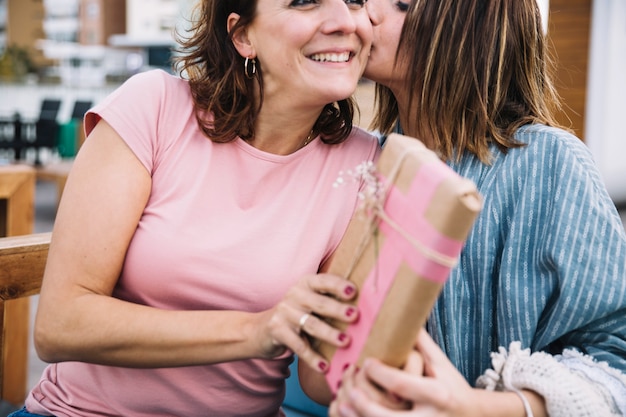 Kostenloses Foto frau, die frau für geschenk küsst