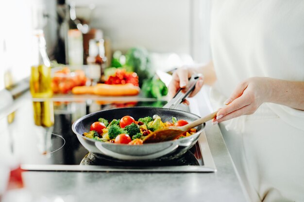 Frau, die Gemüse auf Pfanne kocht