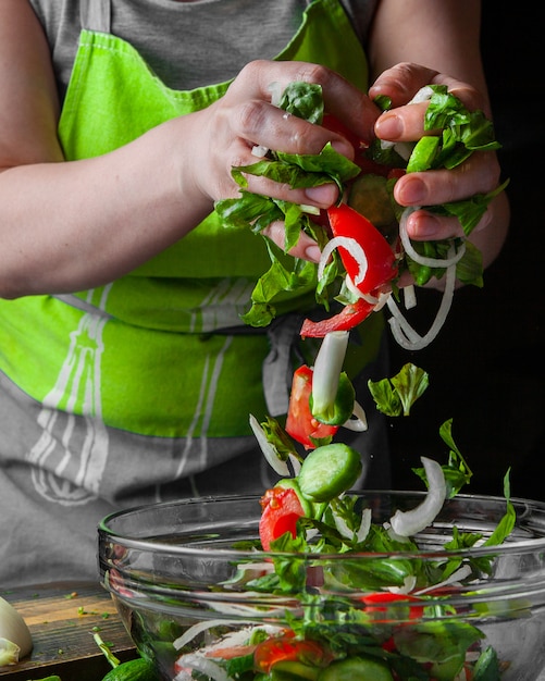 Frau, die Gemüse in die saisonale Salatseitenansicht hinzufügt