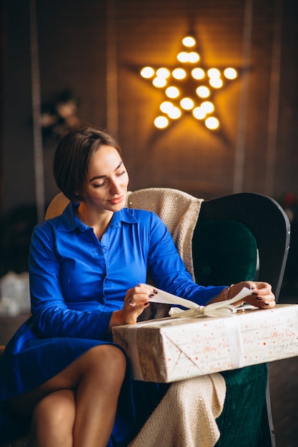 Frau, die Geschenke durch Weihnachtsbaum auspackt