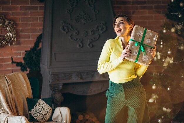 Frau, die Geschenke durch Weihnachtsbaum auspackt