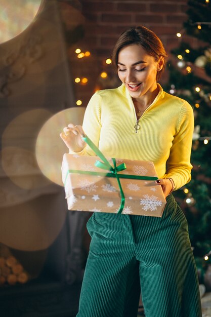 Frau, die Geschenke durch Weihnachtsbaum auspackt