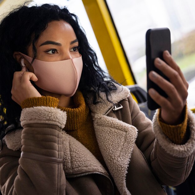 Frau, die Gesichtsmaske im Bus trägt, während Musik in den Ohrhörern hört
