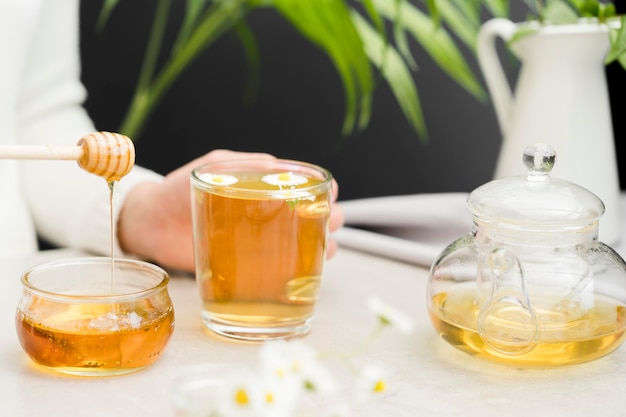 Frau, die Glas mit Tee und Honigschöpflöffel hält